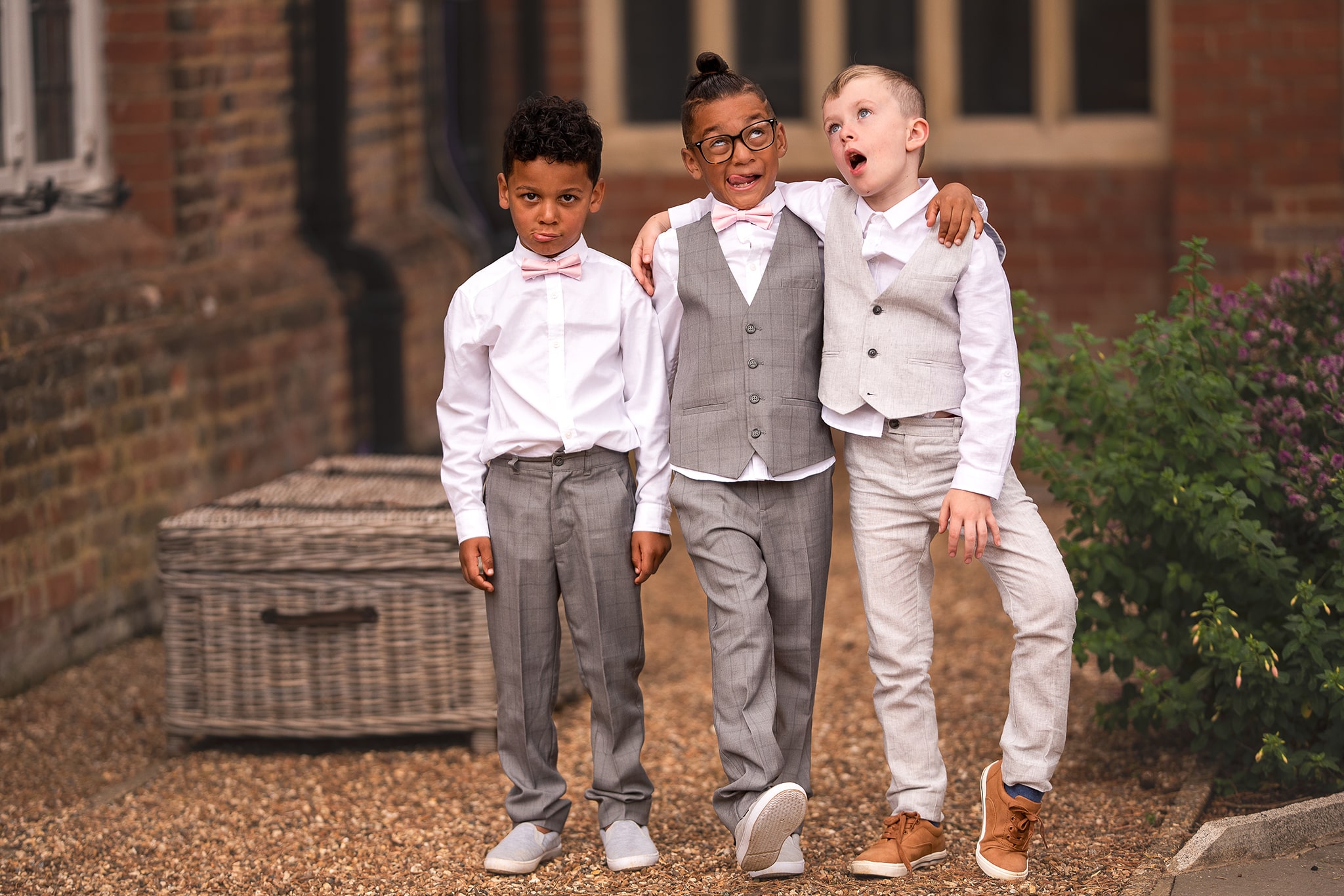 Funny photo of three young boys pulling faces, dressed smartly in wedding suits.